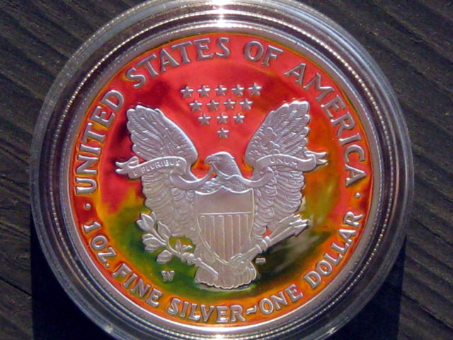 This isn't a colorized coin. Rather it's a proof silver American Eagle coin that's reflecting the colors of the photographer's tie-dye shirt! 
